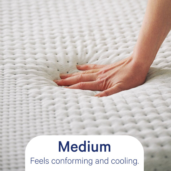 Hand touching a textured mattress surface with text indicating 'Medium' feel.